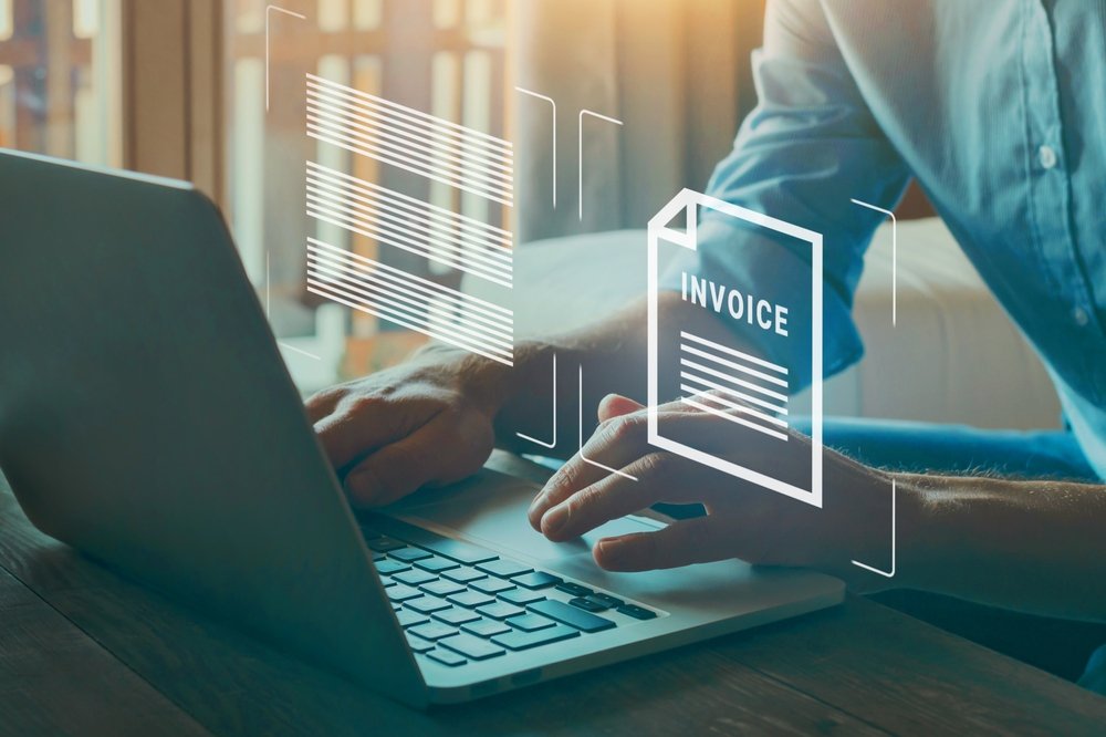 Person working at a laptop with an invoice document graphic overlaid