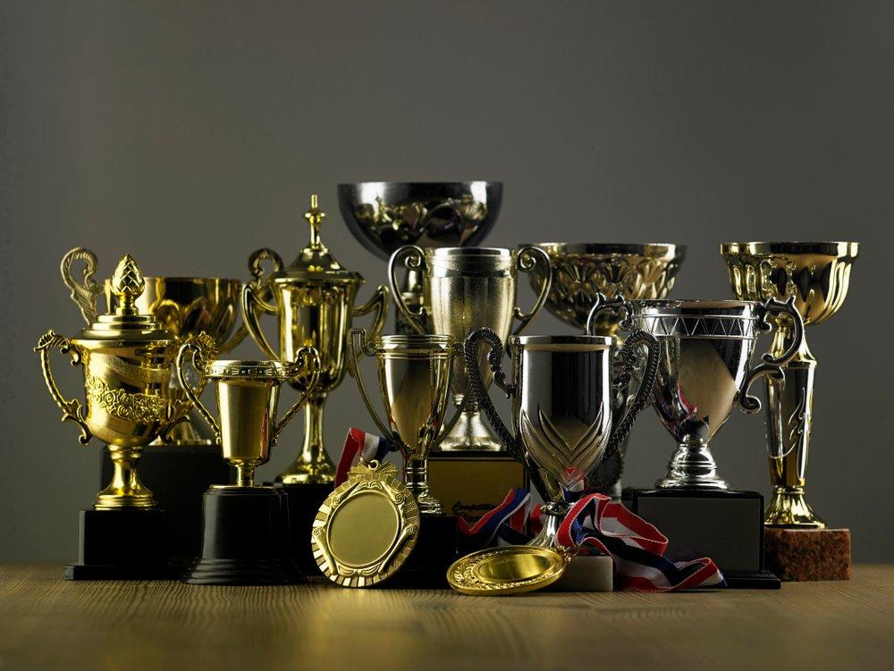 Collection of gold and silver cup trophies and ribboned medals grouped on a wooden surface