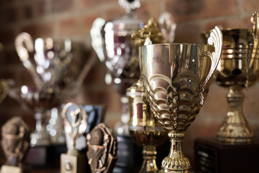 Collection,Of,Gold,Trophies,On,Shelf Row of gold and silver cup trophies on a shelf against a brick wall